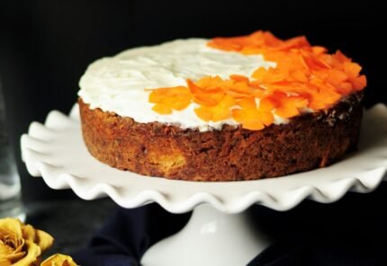 white and orange icing-coated cake on scalloped edge white ceramic cake stand